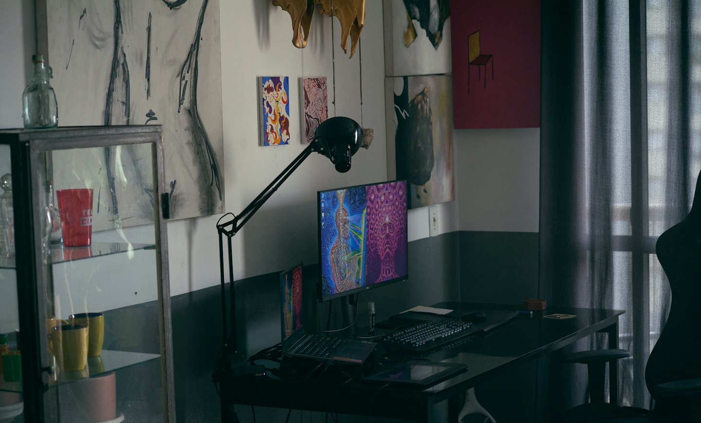 Creative office desk with computer monitor displaying colorful digital art.