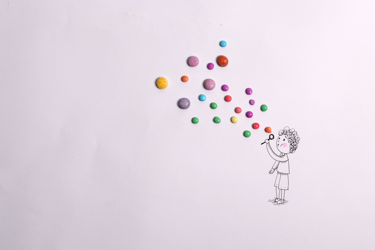 Person blowing colorful candy bubbles on white background.