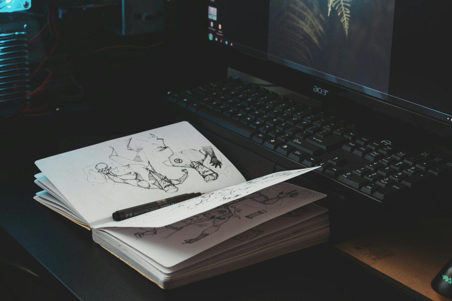 Open sketchbook with character drawings and a pen on a desk.