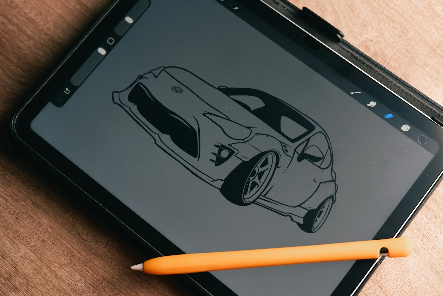 A stylus rests on a tablet displaying a sports car illustration.