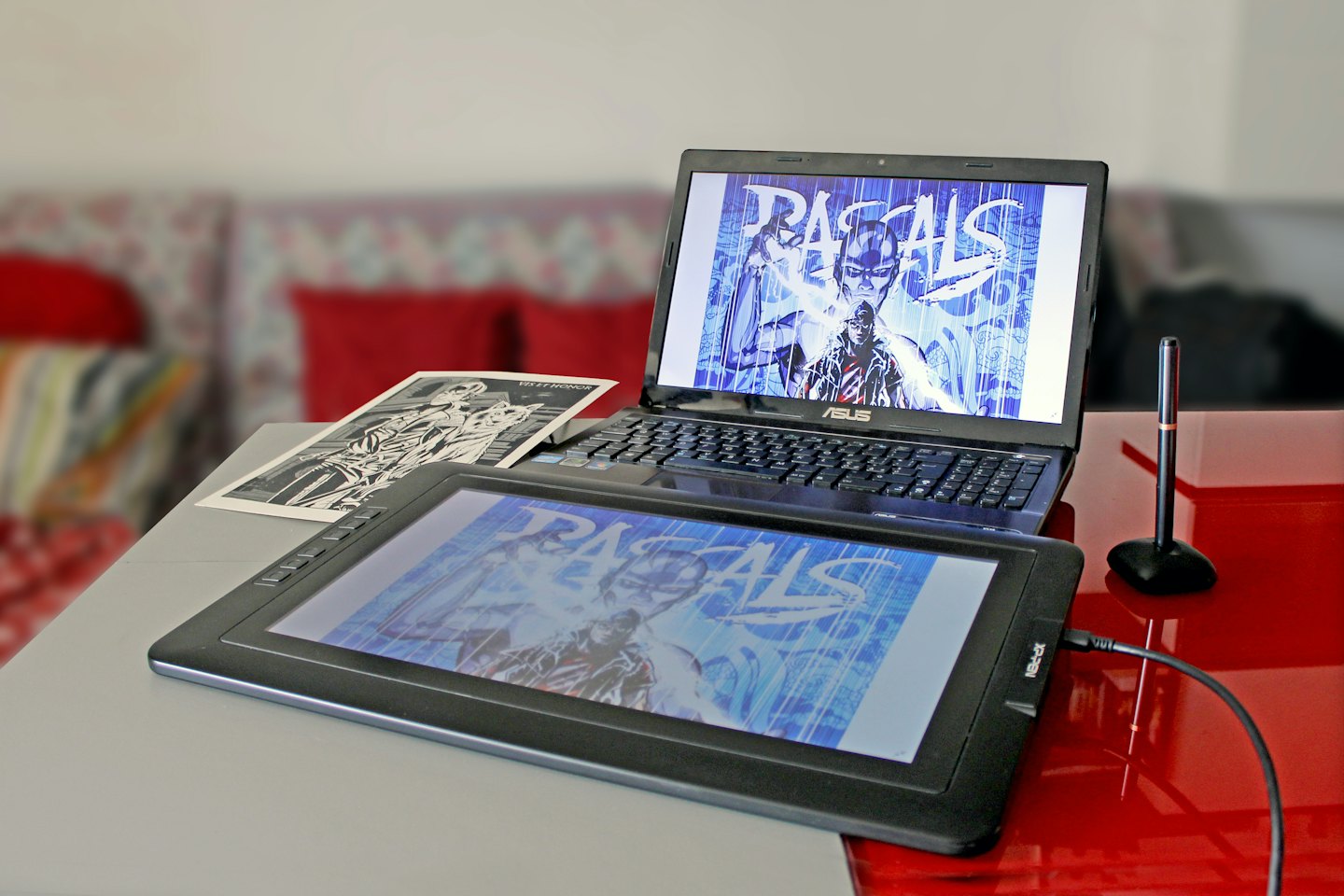 Digital art equipment and comic book sketches on a desk.